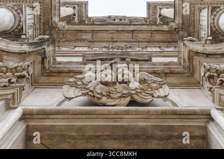 Der Blick auf kunstvoll verzierte Steinschnitzereien von Cherubiken und architektonische Details schafft eine strukturierte, historische Fassade, Sulmona, Abruzzen, Italien. Stockfoto
