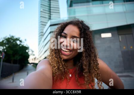 Trendige junge Frau lächelt draußen auf der Straße der Stadt und strahlt Jugendliche Energie aus Stockfoto