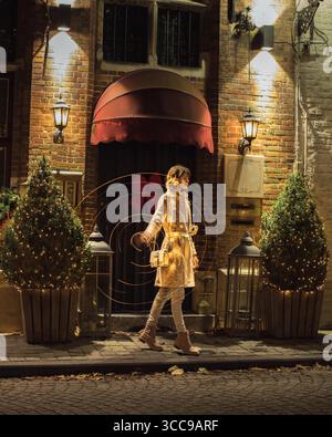 Schöne junge Frau, die seitlich vor dem Eingang des Gebäudes steht, während sie Lichtspuren macht, indem sie sich bewegt und die Lichter in den Händen dreht. Stockfoto