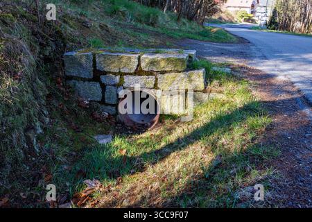 Ein Abflussrohr zur Ableitung von Regenwasser entlang der Straße. Das Rohr ist mit Steinblöcken ausgekleidet. Hochwertige Fotos Stockfoto