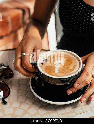 Hände halten Lavendellatte in Black Cup Stockfoto