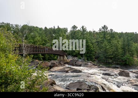 Onaping, Ontario, Kanada. August 2025. Brücke oben auf den Wasserfällen am A.Y. Jackson Lookout. Der A.Y. Jackson Lookout in Onaping, Ontario, bietet einen atemberaubenden Blick auf die High Falls, wo der Onaping River 55 Meter über den Canadian Shield fällt. Benannt nach dem Künstler A.Y. Jackson der Gruppe der sieben, bietet der Ort zugängliche Wanderwege, einschließlich eines selbstgeführten geologischen Spaziergangs, auf dem Besucher die reiche Natur- und geologische Geschichte der Region erkunden können. (Credit Image: © Shawn Goldberg/SOPA Images via ZUMA Press Wire) NUR REDAKTIONELLE VERWENDUNG! Nicht für kommerzielle ZWECKE! Stockfoto