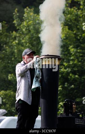 EXETER, DEVON, Großbritannien - 18. MAI 2023 Mann in einer Kappe, der einen rauchenden Schornstein eines Triebwerks reinigt Stockfoto