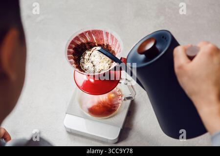 Nahaufnahme des Gießens von Wasser in den Brühtrichter zur Kaffeezubereitung Stockfoto