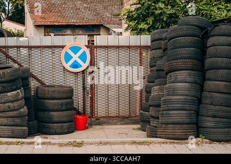 Gestapelte Altreifen in verschiedenen Laufflächenmustern, in hohen Stapeln angeordnet, in Schwarzweiß fotografiert für einen rauen industriellen Textureffekt. Selektiv Stockfoto