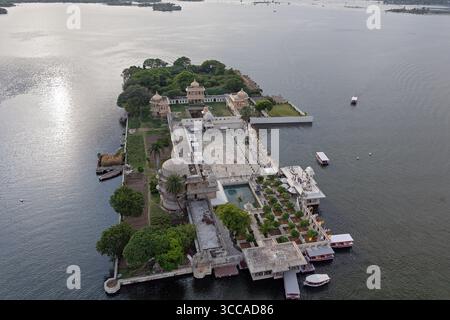 Aus der Vogelperspektive auf den glitzernden Pichola-See, der den großen Jag Niwas umschließt, auch bekannt als Lake Palace, mit seiner weißen Marmorfassade, die das sanfte Licht reflektiert, Udaipur, Rajasthan, Indien. Stockfoto
