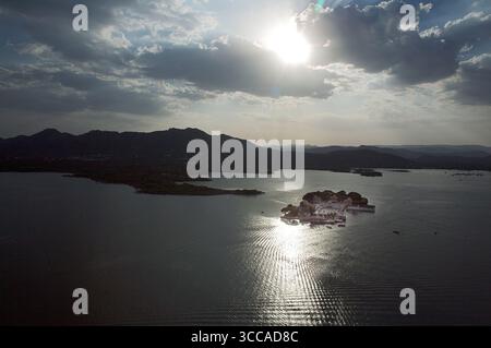 Aus der Vogelperspektive auf das glitzernde Wasser, das die Sonne in der Nähe des Jag Niwas reflektiert, im Kontrast zu den dunklen Hügeln, Udaipur, Rajasthan, Indien. Stockfoto