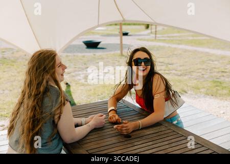 Zwei fröhliche Frauen lachen und unterhalten sich bei einem Weinevent im Freien Stockfoto