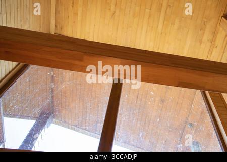Großes dreieckiges Fenster mit Spinnweben und Schmutz im Holzhaus rustikale Innenreinigung erforderlich Stockfoto
