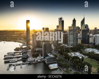 Perth, Australien - 08. Juni 2025: Aus der Vogelperspektive auf die Uferpromenade der Esplanade mit Booten, die entlang des Swan River angedockt sind, während die Sonne einen goldenen Glanz über sich wirft Stockfoto
