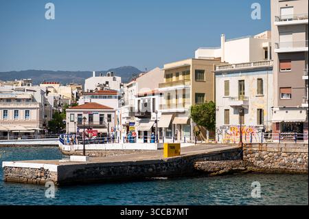 Agios Nikolaos, Kreta, Griechenland - 26. Juni 2025: Die Menschen schlendern entlang der Uferpromenade in Agios Nikolaos, Kreta, unter klarem blauem Himmel. Stockfoto