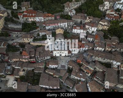 Blick aus der Vogelperspektive auf sonnenverwöhnte Terrakottadächer und weiße Steinbauten, die sich um die zentrale Kirche in der antiken Stadt Morcone, Benevento, Kampanien, Italien gruppieren. Stockfoto