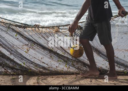 Der halbe Körper eines nicht identifizierten Fischers, der ein Fischernetz zieht. Fisch und Meeresfrüchte, Hobby. Brasilien Stockfoto