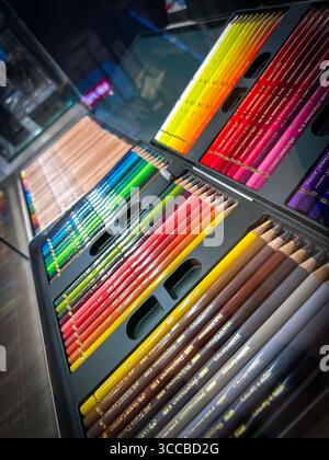 Eine vielfältige Auswahl an Regenbogenfarbenen Bleistiften, die in einem offenen Etui angeordnet sind und auf einem Ladentisch unter heller Beleuchtung ausgestellt sind Stockfoto