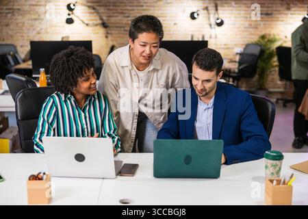 Multiethnisches Team arbeitet an Projekten mit Laptops in modernen Büros zusammen Stockfoto