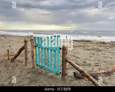 Holzzaun mit türkisfarbenem Holztor am Strand Stockfoto