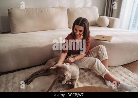 Eine Frau genießt eine schöne Zeit mit ihrem geliebten Hund in einem gemütlichen Wohnzimmer Stockfoto