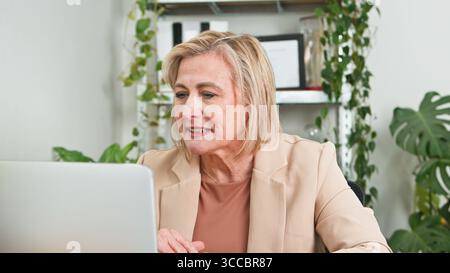 Senior Frau, die in einem Business Setting arbeitet, umgeben von Grün Stockfoto