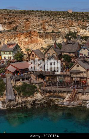 Mit Blick auf Popeye Village in Anchor Bay, Malta, an einem sonnigen Tag mit hellblauem Himmel und einem farbenfrohen Dorf mit Filmkulisse und Küste. Stockfoto
