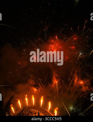Feuerrotes Feuerwerk und Flammenstrahlen brechen während einer Abendfeier über einer Kuppelstruktur aus Stockfoto