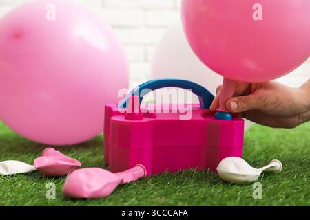 Frau, die einen Ballon mit Luftpumpe im Haus aufbläst, Nahaufnahme Stockfoto