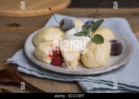 Traditionelles ukrainisches Gericht – faule Knödel aus weichem Hüttenkäse mit saftigen Kirschen im Inneren. Hausgemachte Küche, lecker und einfach zuzubereiten Stockfoto