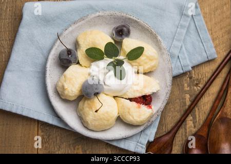 Traditionelles ukrainisches Gericht – faule Knödel aus weichem Hüttenkäse mit saftigen Kirschen im Inneren. Hausgemachte Küche, lecker und einfach zuzubereiten Stockfoto