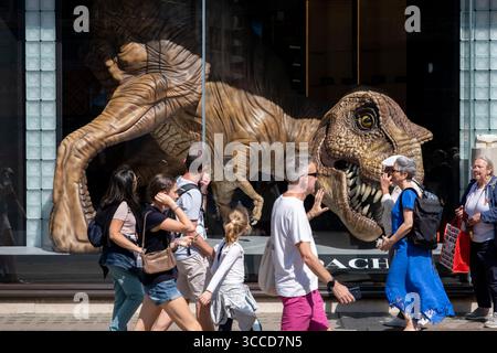 Käufer und Besucher interagieren mit einem großen T-Rex-Dinosaurier im Schaufenster von Coach Out on Regent Street am 8. August 2025 in London, Großbritannien. Die Regent Street ist ein bedeutendes Einkaufszentrum im West End der Hauptstadt und ist bekannt für seine Flaggschiff-Einzelhandelsgeschäfte, von denen die meisten Mode-, High Street- und High-End-Bekleidungsgeschäfte sind. Stockfoto