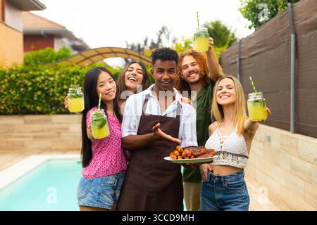 Verschiedene Gruppen von Freunden feiern, Limonade und gegrilltes Essen halten und den Sommer am Swimmingpool genießen Stockfoto