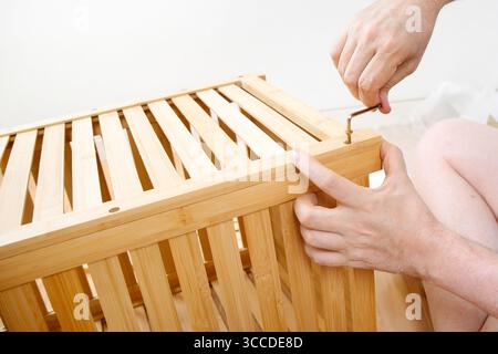 Hände mit inbusschlüssel-Befestigungsschraube an selbstmontierenden Holzmöbeln Stockfoto