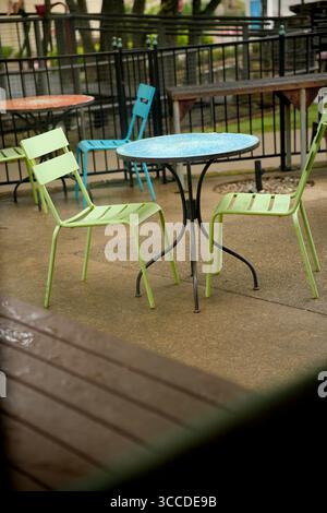 Leere bunte Metalltische und -Stühle stehen auf einer Terrasse und laden Gäste zum Sitzen und Entspannen ein Stockfoto