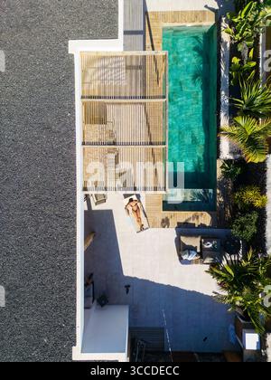 Aus der Vogelperspektive auf eine Frau, die sich in der Nähe eines privaten Swimmingpools in einem Luxusresort sonnt Stockfoto