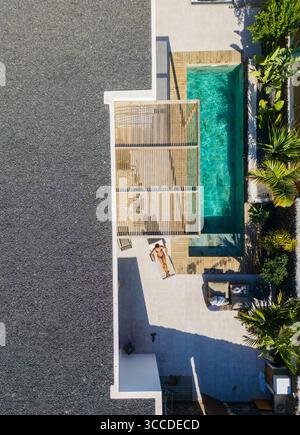 Aus der Vogelperspektive auf eine Frau, die sich in der Nähe eines privaten Tauchpools in einem Luxusresort sonnt Stockfoto