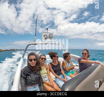 Fünf fröhliche junge Frauen, die an einem sonnigen Tag eine Fahrt mit dem Schnellboot genießen und gemeinsam bleibende Erinnerungen schaffen Stockfoto