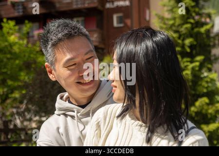 Glückliches asiatisches Paar lächelt und teilt einen zarten Moment draußen in den Bergen Stockfoto