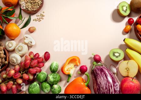 Rahmen aus Obst, Gemüse und einer Schüssel Linsen, gesunde Ernährung flach liegen auf beigem Hintergrund. Draufsicht, Kopierraum Stockfoto