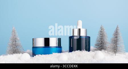 Schönheitskonzept für die Winterpflege mit Kosmetikprodukten und Weihnachtsdekorationen auf blauem Hintergrund, Vorderansicht, Kopierraum Stockfoto