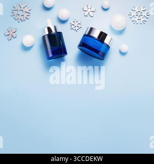 Schönheitskonzept für die Winterpflege mit Kosmetikprodukten und Weihnachtsdekorationen auf blauem Hintergrund, Draufsicht, Kopierraum Stockfoto