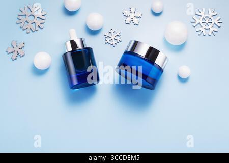 Schönheitskonzept für die Winterpflege mit Kosmetikprodukten und Weihnachtsdekorationen auf blauem Hintergrund, Draufsicht, Kopierraum Stockfoto
