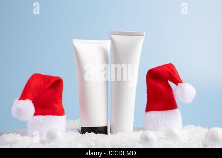 Schönheitskonzept für die Winterpflege mit Kosmetikprodukten mit Weihnachtsmütze, Weihnachtsdekorationen auf blauem Hintergrund, Vorderansicht, Kopierraum Stockfoto