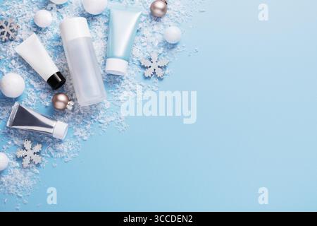 Winterpflege- und Schönheitskonzept mit Kosmetikprodukten und Weihnachtsdekorationen auf blauem Hintergrund, Draufsicht, Kopierraum Stockfoto