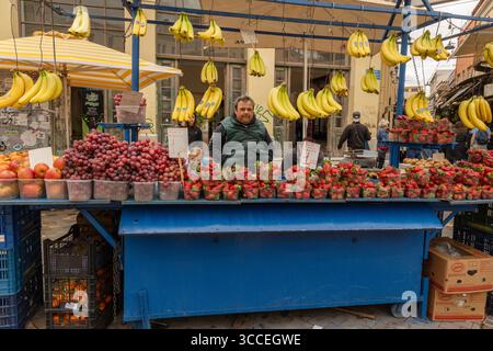 Blick auf die Straße, Nahaufnahme eines Mannes, der Obst an einem belebten Straßenstand in Athen, Griechenland, arrangiert. Stockfoto