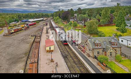 Strathspey Railway Boat von Garten Station Schottland die Dampfeisenbahn kommt am Bahnsteig an und blumenbedeckte Gebäude Stockfoto
