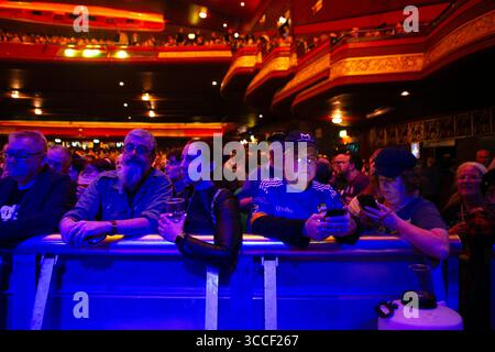 Musikbesucher auf ihren Mobiltelefonen, während die Pogues auf die Bühne im O2 Apollo in Manchester, England, warten. Stockfoto