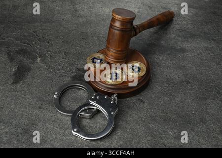 Kryptowährung. Bitcoins, Hammer und Handschellen auf grauem Tisch Stockfoto