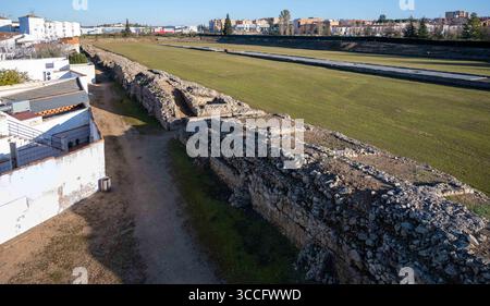 Blick aus der Vogelperspektive auf den antiken römischen Zirkus von Mérida, Spanien, neben einem grasbewachsenen Feld, mit modernen Gebäuden im Hintergrund Stockfoto
