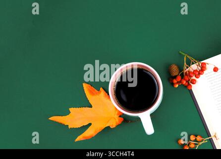 Eine Tasse Kaffee steht auf grünem Hintergrund, neben Ahornblättern und rowan Stockfoto