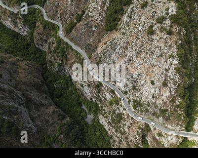 Aus der Vogelperspektive schlängelt sich eine gewundene Straße durch zerklüftete Klippen, ein graues Band vor der wilden, strukturierten Landschaft, Gole del Sagittario, Abruzzen, Italien. Stockfoto