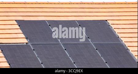 Nahaufnahme von Solarpaneelen, die auf einem Ziegeldach installiert sind, um erneuerbare Solarenergie zu nutzen Stockfoto