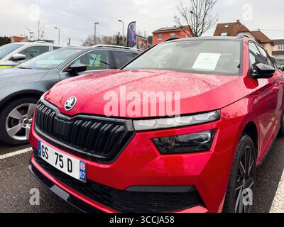 Paris, Frankreich - 6. Dezember 2023: Roter Skoda-SUV wird an einem regnerischen Tag im Elsass im Autohaus ausgestellt, mit Regentropfen auf der Motorhaube und durchsichtigem Preisschild Stockfoto